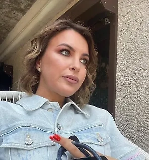 На девушке надето изысканное кольцо, выполненное известным брендом Graff, который славится своими уникальными ювелирными изделиями и высоким качеством. Основной материал этого украшения — платина, которая отличается своей прочностью, долговечностью и благородным серебристым оттенком. <...>  В центре кольца расположен крупный бриллиант огранки кушон весом 3 карата, который привлекает внимание своей яркостью и игрой света.