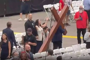 На стадион, где проходит прощание с Кирком, верующие принесли деревянный крест